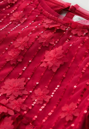 Tissu rouge avec motifs floraux et accents de sequins. Présente un col rond et une texture lisse, mettant en valeur des détails et des ornements délicats.