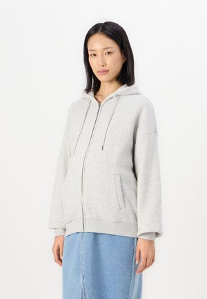 Ljusgrå zip-up hoodie med snoddhuva, kängurufickor och lösa ärmar, i kombination med en ljusblå denimkjol. Slät textur.