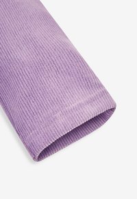 Fialová kordurová látka s jemně vroubkovanou strukturou, rolled edge a měkkým dotykem. Detailní pohled na její barvu a materiál.