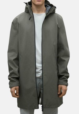 Chaqueta de lluvia color caqui con una silueta larga, que presenta un cierre de cremallera, capucha con cordón, bolsillos laterales y puños elásticos. Textura suave.