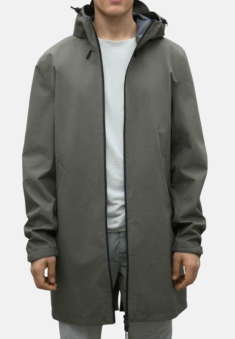 Chaqueta de lluvia color caqui con una silueta larga, que presenta un cierre de cremallera, capucha con cordón, bolsillos laterales y puños elásticos. Textura suave.