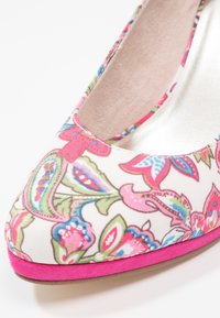 Chaussure à talon haut à motif floral avec des dessins cachemire roses, bleus et verts et un bord de semelle rose vif, vue de face latérale.