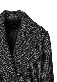 Cappotto a zigzag bianco e nero con ampio rever, realizzato in tessuto testurizzato. Etichetta che recita "CALLIOPE," taglia piccola.