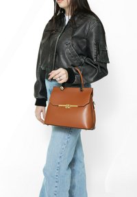 Borsa in pelle marrone con chiusura dorata, forma strutturata, parte superiore piatta e base arrotondata. Tessuto liscio con due manici superiori e hardware minimale.