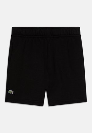 Sorte elastiske taljeshorts med en lille grøn Lacoste krokodillelogo på det nederste venstre ben mod en hvid baggrund.