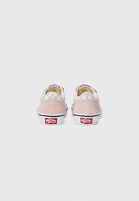 Ružové semišové a kárované látkové slip-on topánky s bielym interiérom a čiernou gumovou podrážkou. Na päte sa nachádza červené logo Vans.
