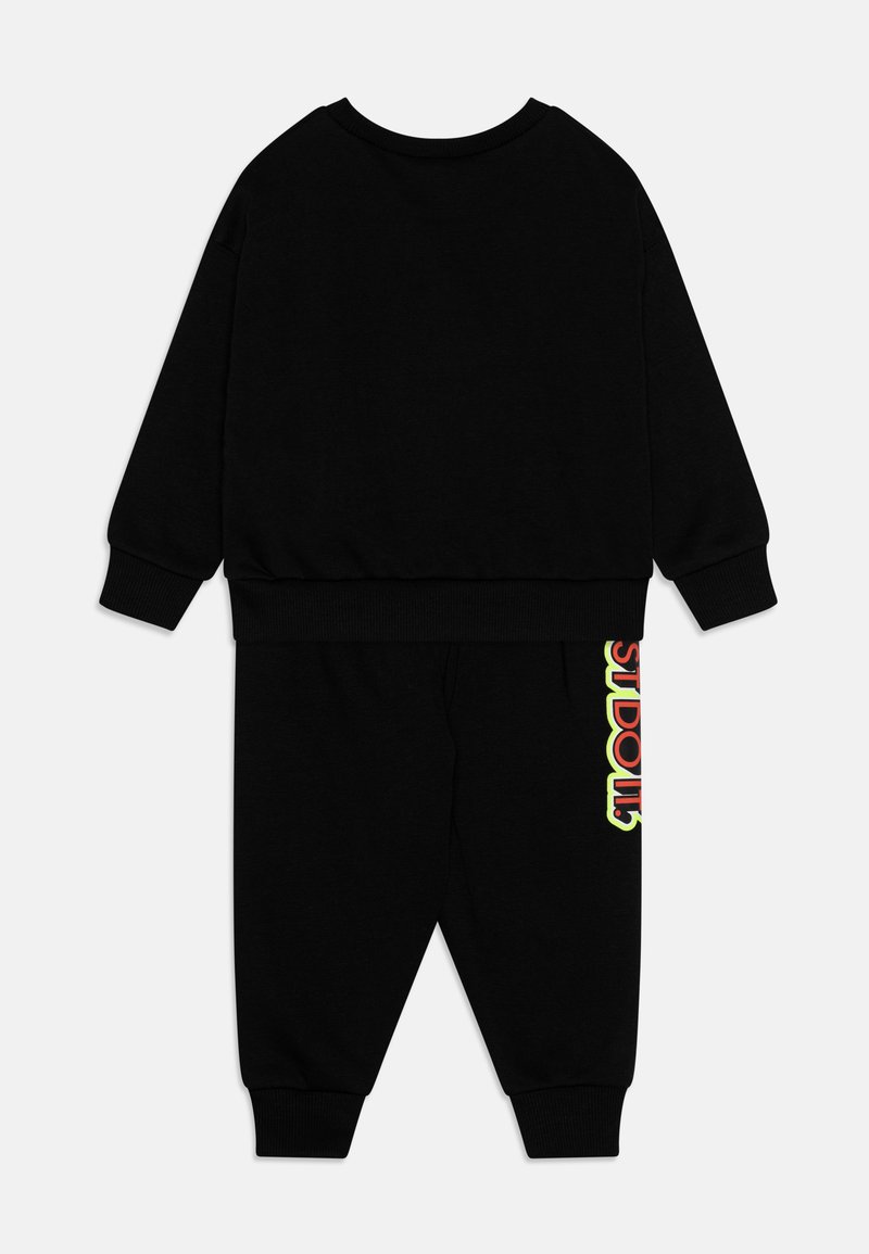 Schwarzes Zweiteiliges Outfit aus weichem Stoff. Besteht aus einem Sweatshirt mit Rundhalsausschnitt und Jogginghosen mit einem bunten Grafikdesign an der Seite.