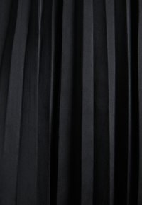 Tissu noir plissé avec des plis verticaux créant un aspect texturé et superposé.