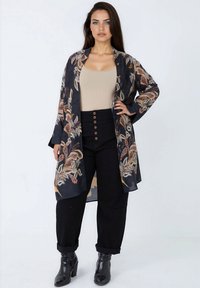 Black kimono with colorful leaf patterns, lightweight fabric, open front, long sleeves, paired with beige top and high-waisted black pants.