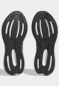 Suelas de zapatillas deportivas negras con acentos blancos. Material de goma texturizada con surcos y patrones para agarre y flexibilidad. Marca Cloudfoam visible.