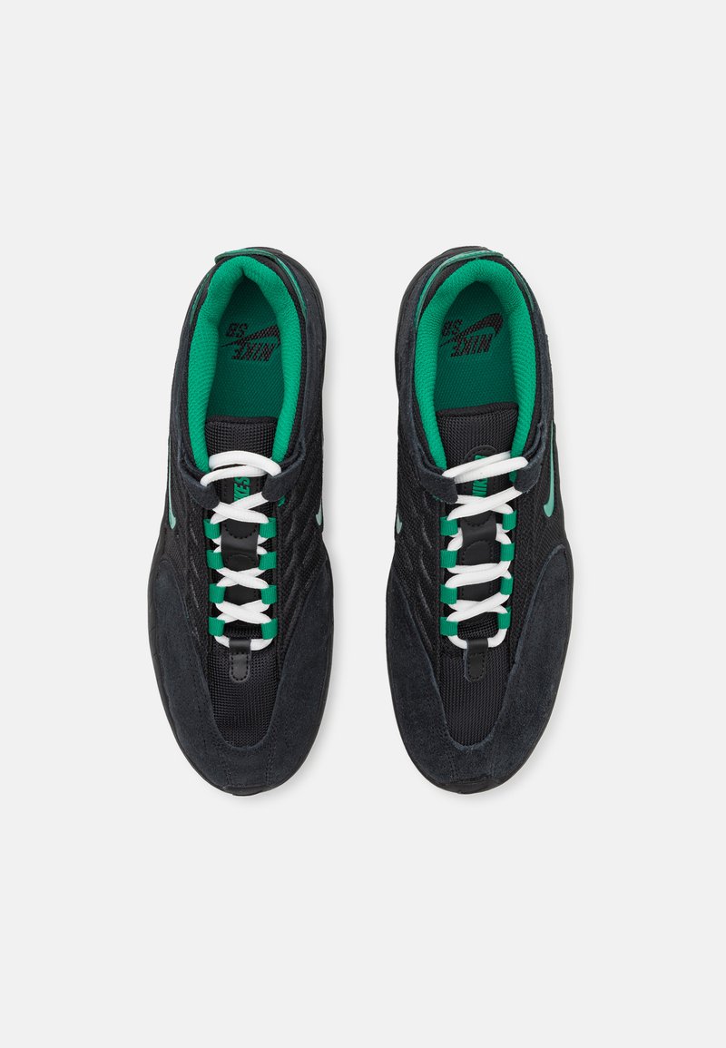 Schwarze Wildleder- und Mesh-Sneaker mit weißen und grünen Schnürsenkeln, mit einer abgerundeten Spitze und dicker Sohle. Grüne Innenausstattung und Logodetail.