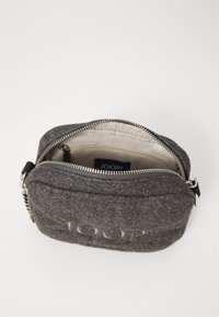 Borsa grigia in feltro con chiusura a zip, caratterizzata da un logo in rilievo e un interno foderato in tessuto con una piccola tasca. Finiture in metallo argento.
