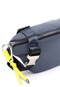 Granatowa torba z zamkiem błyskawicznym, wykonana z teksturowanej tkaniny, z metalowymi srebrnymi elementami oraz żółtym akcentem w postaci paska. Posiada elegancki, prostokątny kształt.