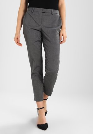 Pantalons gris ajustés avec une coupe slim, texture lisse et motif à carreaux subtil ; associés à des escarpins noirs à bride de cheville.