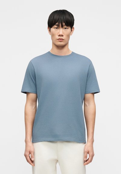 T-shirt à col rond en coton doux et léger. Il présente une coupe décontractée, des manches courtes et une couleur unie bleu clair. Design simple.