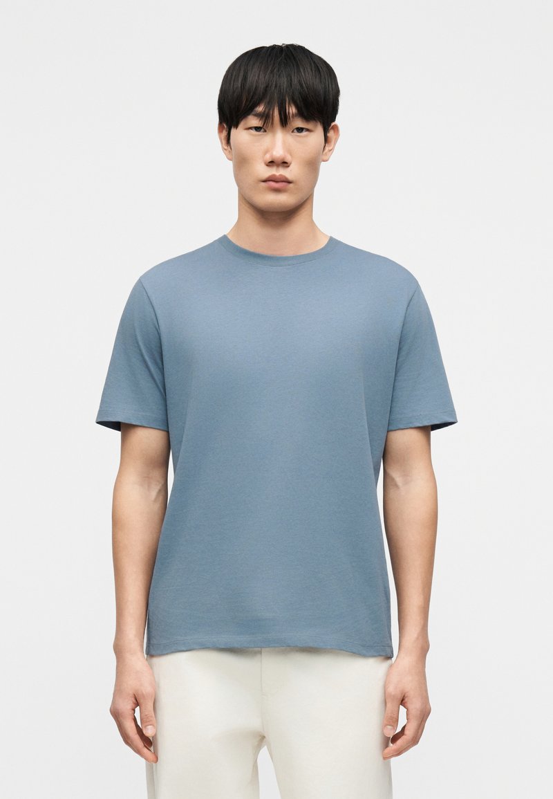 T-shirt à col rond en coton doux et léger. Il présente une coupe décontractée, des manches courtes et une couleur unie bleu clair. Design simple.