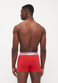 Rote Boxershorts aus weichem Stoff, mit einem weißen Bund und dem Logo "JACK & JONES". Enganliegendes Design mit glatter Oberfläche.