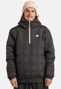 Pikowana czarna kurtka z półzamkiem z przodu, kapturem, elastycznymi mankietami i logotypem na piersi. Charakteryzuje się teksturowanymi okrągłymi wzorami.