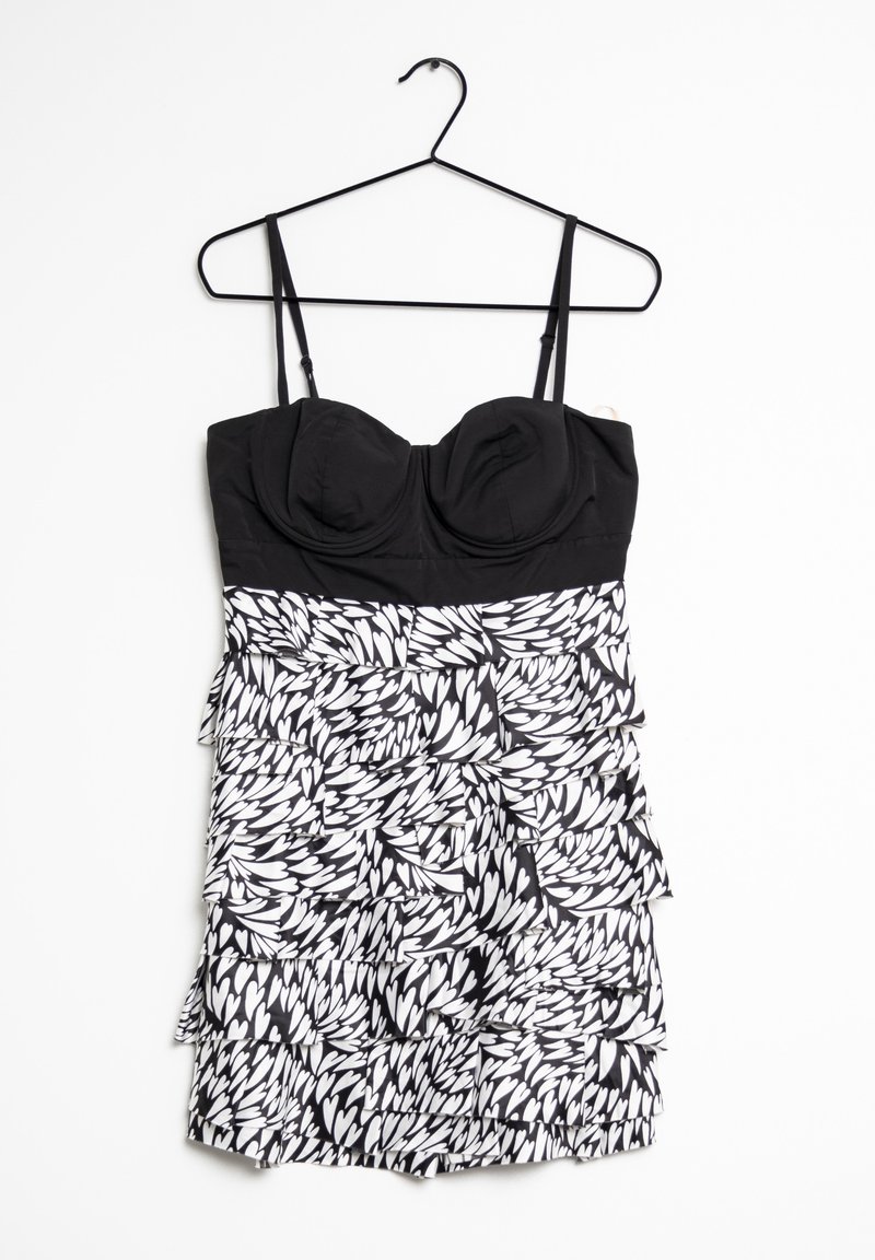 Abito in bianco e nero con top aderente caratterizzato da coppe sagomate, spalline sottili e una gonna a strati con rouches e motivi a foglia.