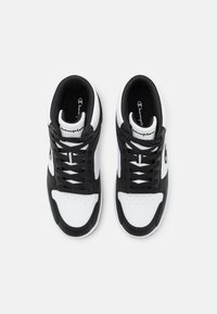 Sneakers atletici bianco e nero con tomaia in pelle liscia, punta tonda, design con lacci e logo Champion sulla linguetta.
