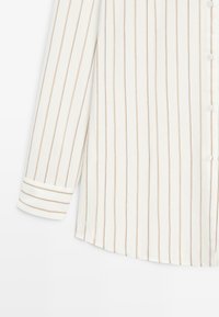 Witte blouse met lange mouwen, verticale lichtbruine strepen en knoopmanchetten, voorzien van een knoopsluiting aan de voorkant.