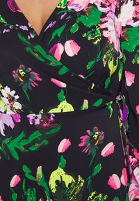 Černá látka s živým, multibarevným květinovým vzorem, obsahující velké růžové a žluté květiny, zelené listy a design s překrytím se zavazovacím detailem.