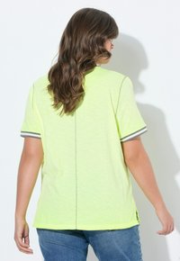 T-shirt giallo fluorescente a maniche corte con accenti a strisce grigie sulle maniche, caratterizzato da una vestibilità comoda e fessure laterali all'orlo.