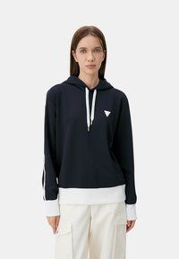 Felpa navy con cordini e orlo bianchi, caratterizzata da un piccolo logo triangolare sul petto. Realizzata in tessuto morbido con una vestibilità rilassata.