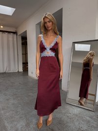 Burgundy satin maxi dress with lace trim, deep neckline, and cut-out detail. Complemented by beige pointed-toe heels and a full-length mirror.