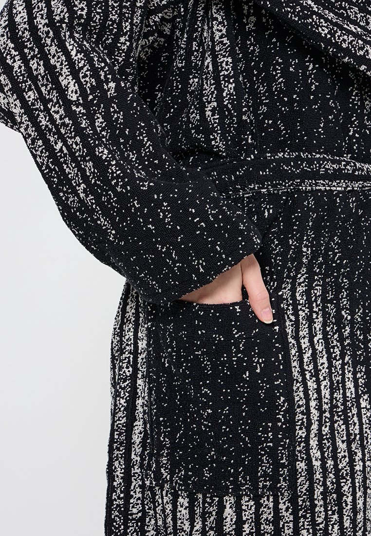 Cappotto nero a maglia con un motivo a righe testurizzato bianco, con una tasca frontale e maniche lunghe. Materiale morbido progettato per il calore.