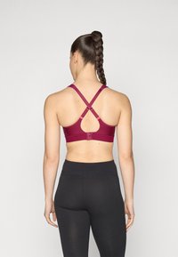 Maron sportBH med nøkkelhullsutskjæring, kryssryggstropper og justerbar hardware. Glatt stoff med subtile perforeringer for ventilasjon.