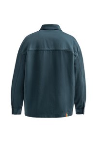 Giacca oversized di un teal scuro con colletto, maniche lunghe e orlo dritto. Presenta un'etichetta con logo sottile sul lato sinistro in basso.