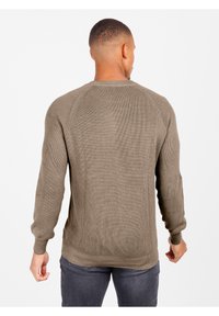 Brauner gerippter Pullover mit langen Ärmeln und rundem Ausschnitt, der ein strukturiertes Strickmuster und einen geraden Schnitt in der Taille aufweist.
