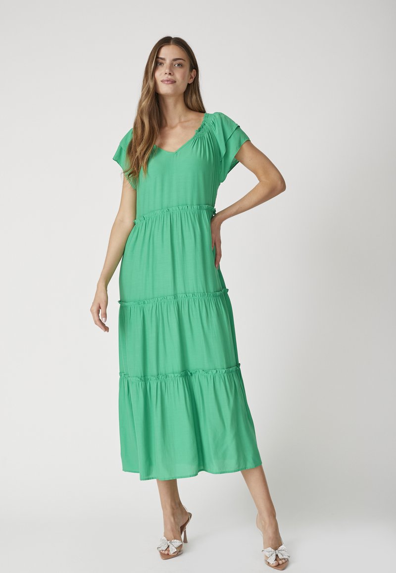 Rochie midi verde dintr-un material ușor, cu decolteu în V, mâneci scurte cu volănașe, design în straturi și detalii pliate la talie.