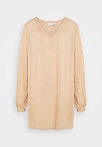 Tunique beige à manches longues avec un col en V, dotée d'une patte de boutonnage sur le devant et de poignets légèrement froncés, fabriquée à partir d'un matériau lisse et doux.