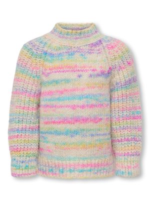 Jeune fille marchant, portant un pull tricoté à rayures pastel, un jean bleu et des baskets blanches sur un fond clair uni.