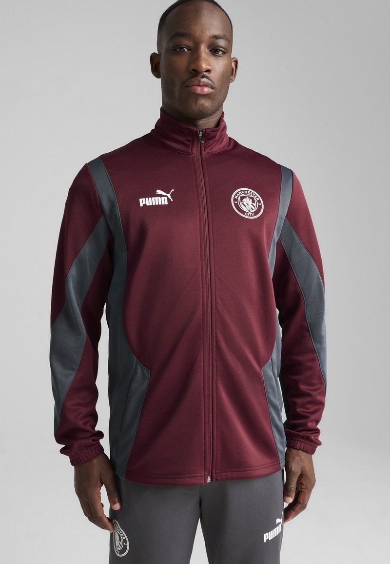 Maron atletisk jakke med grå accenter, lynlås lukning, høj krave og logo på brystet. Glat stof med tætsiddende design og ribbede manchetter.
