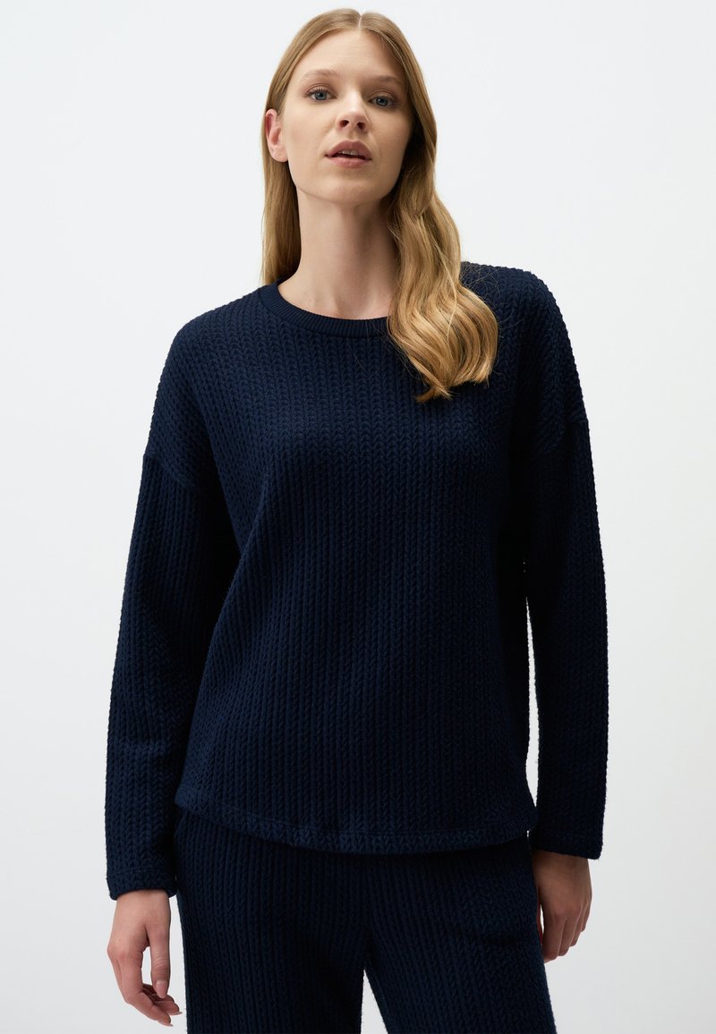 Navyblaue, strukturierte Strickjacke mit Rundhalsausschnitt und langen Ärmeln, die eine lockere Passform hat und einen Saum, der auf den Hüften endet.