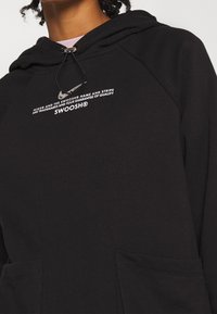 Schwarzer Kapuzenpullover mit einer Fronttasche, ausgestattet mit einem aufgedruckten Nike-Logo und Text. Hergestellt aus weichem Stoff, mit Kordelzugverschluss.