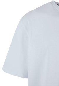 Balta kokvilnas T-krekls ar apaļu kakla izgriezumu un īsām piedurknēm. Audums ir gluds, ar minimālu dizainu un bez redzamām rakstainēm.