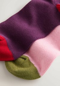 Strikkede sokker med mørkerød tå, lilla skaft, og lyserøde og grønne accenter. Tekstureret stof med en glat finish.