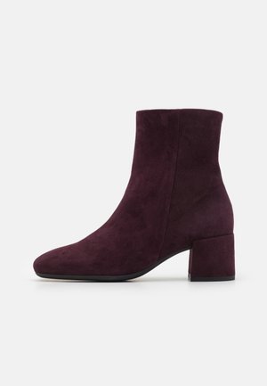 Bottines bordeaux en daim avec un bout arrondi, un talon bloc moyen et une texture lisse ; elles présentent un design minimaliste sans éléments métalliques visibles.