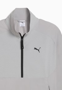 Chaqueta de media cremallera gris claro con cuello, que presenta un patrón texturizado, cremallera negra y un logo negro en el lado izquierdo del pecho.