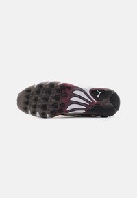 Puma sneaker sole features a multi-colored design with a beige base, black accents, and a textured rubber surface for grip.