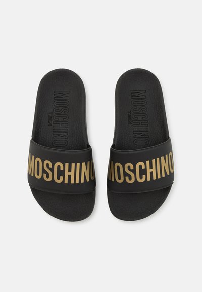 Schwarze Rittsandalen mit einem strukturierten Riemen, auf dem "MOSCHINO" in fetten goldenen Buchstaben gedruckt ist. Bequeme Fußbett mit leichter Polsterung.