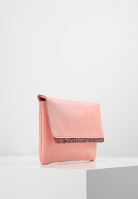 Borse a tracolla in pelle rosa con una finitura testurizzata e un bordo scintillante lungo la parte superiore. Chiusura a pattina, forma rettangolare, esterno liscio.