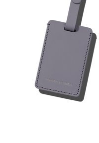 Étiquette de bagage en cuir gris avec un bord cousu, dotée d'une attache en boucle et du texte en relief "HORIZN STUDIOS" sur le devant.