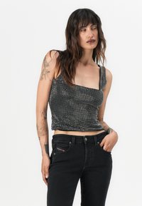 Black and white polka dot crop top with square neckline and thin straps, paired with fitted black jeans featuring a side pocket detail.