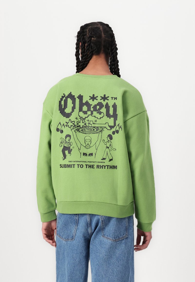 Hanorac verde cu un design grafic negru și text pe spate. Croială lejeră, cu mâneci strâmte și tiv din material ribbit, fabricat dintr-o țesătură moale.