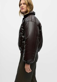 Braune, glänzende, gepolsterte Bomberjacke mit hohem Kragen und elastischen Bündchen, ausgestattet mit Seitentaschen und einer schlanken Silhouette.